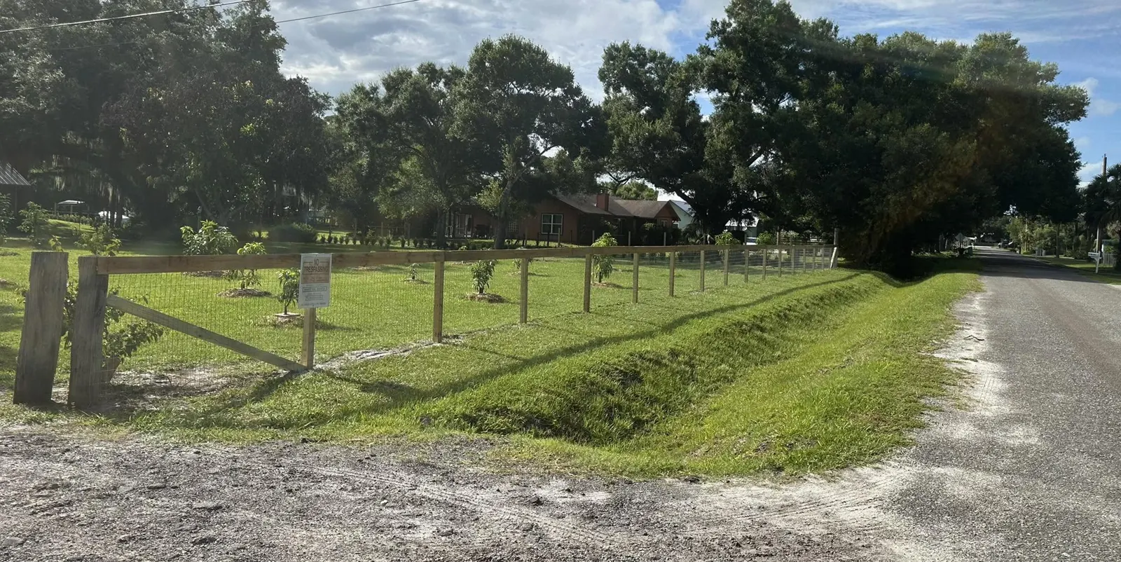 Field fence with wood posts beside a property access lane