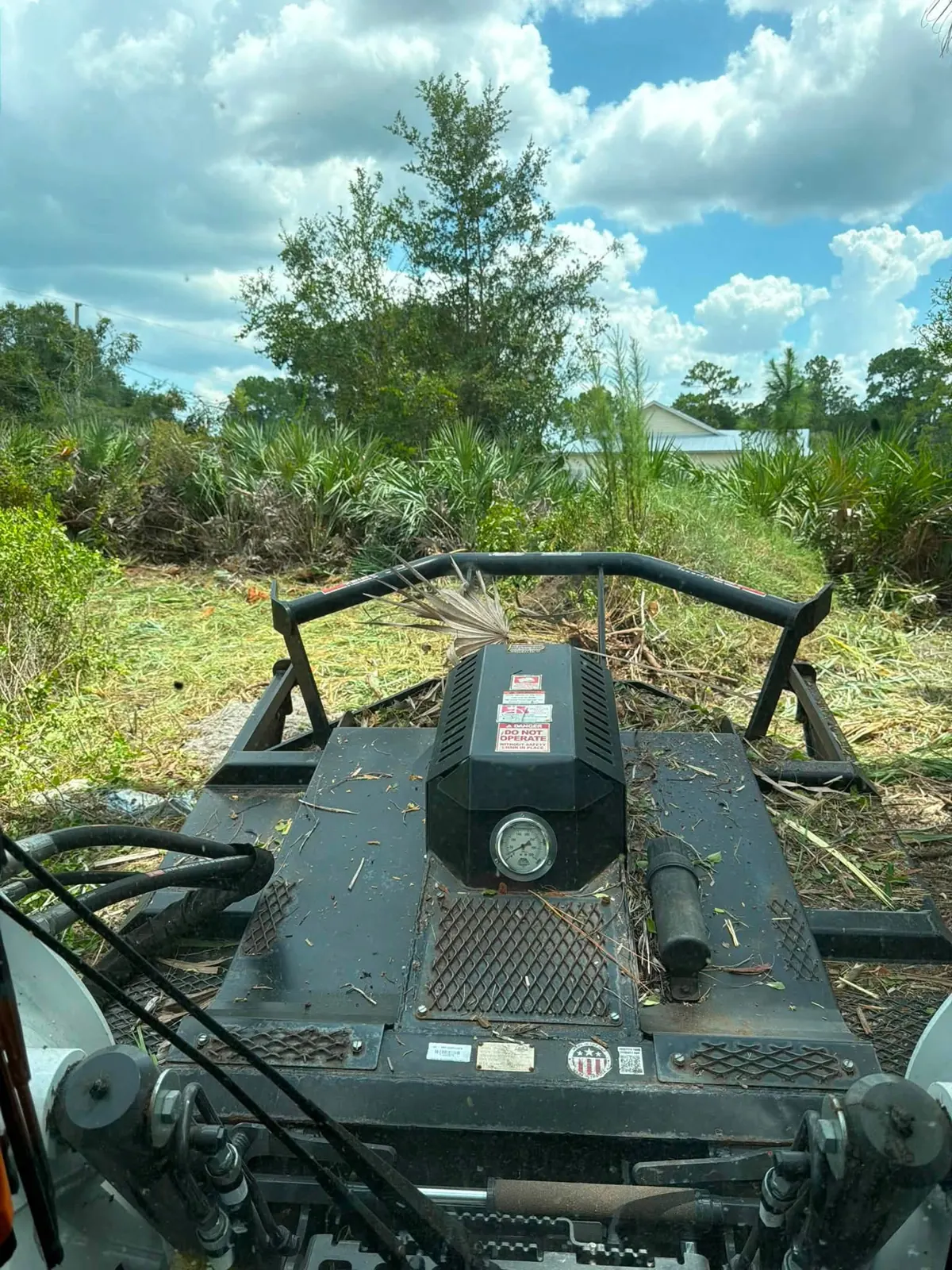 Skid steer working through vegetation on the residential lot